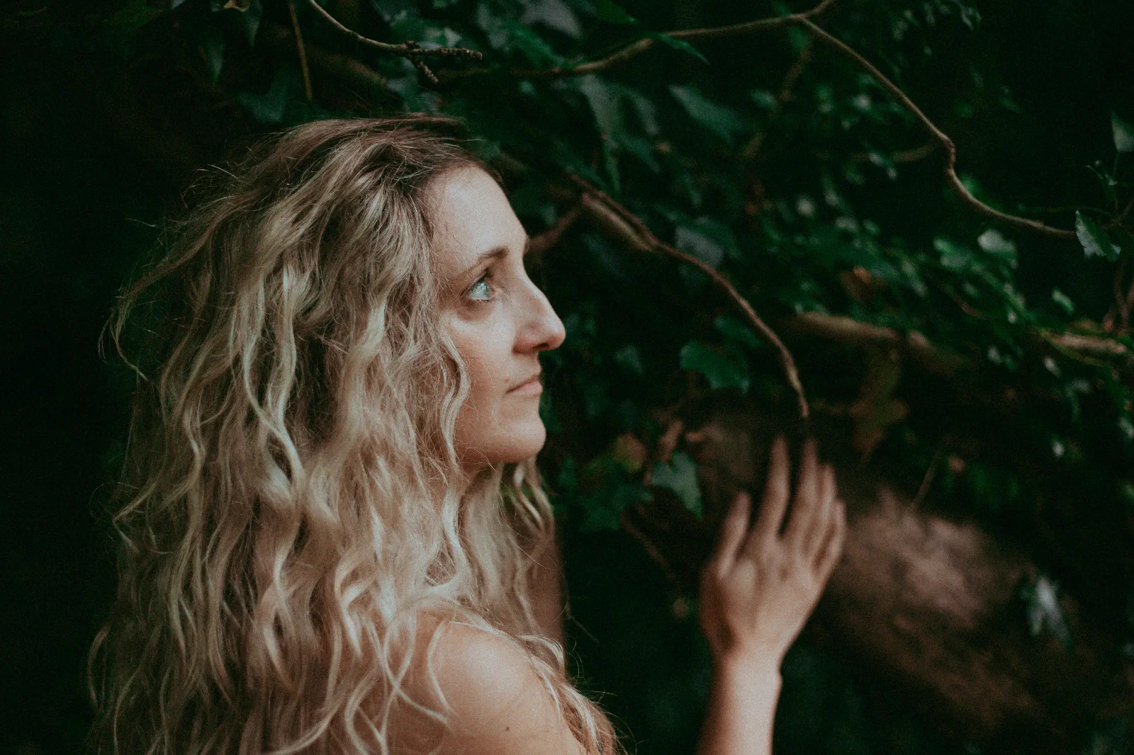 Samantha in gentle profile beside an ivy-covered tree